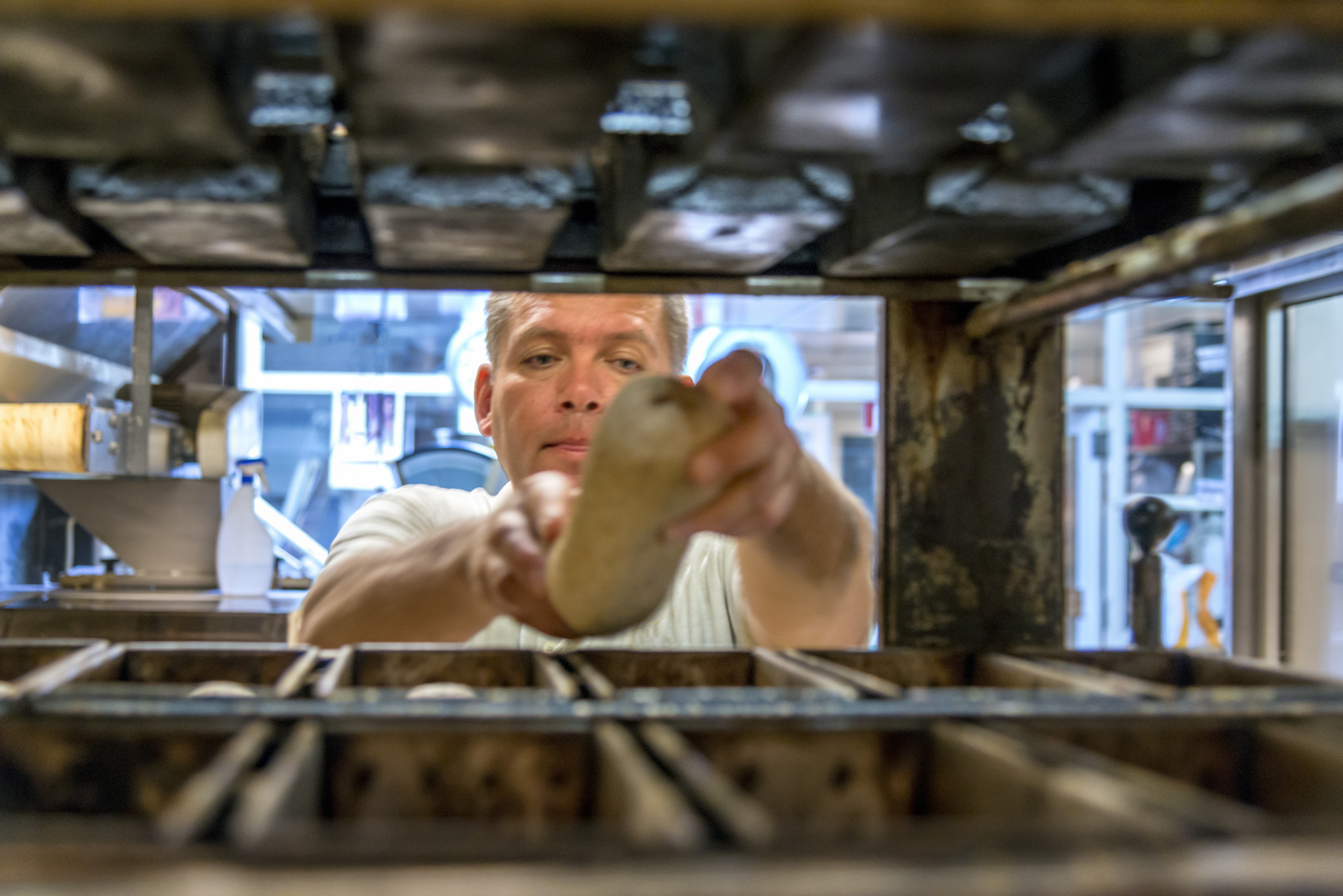 Baker getting bread from the oven
